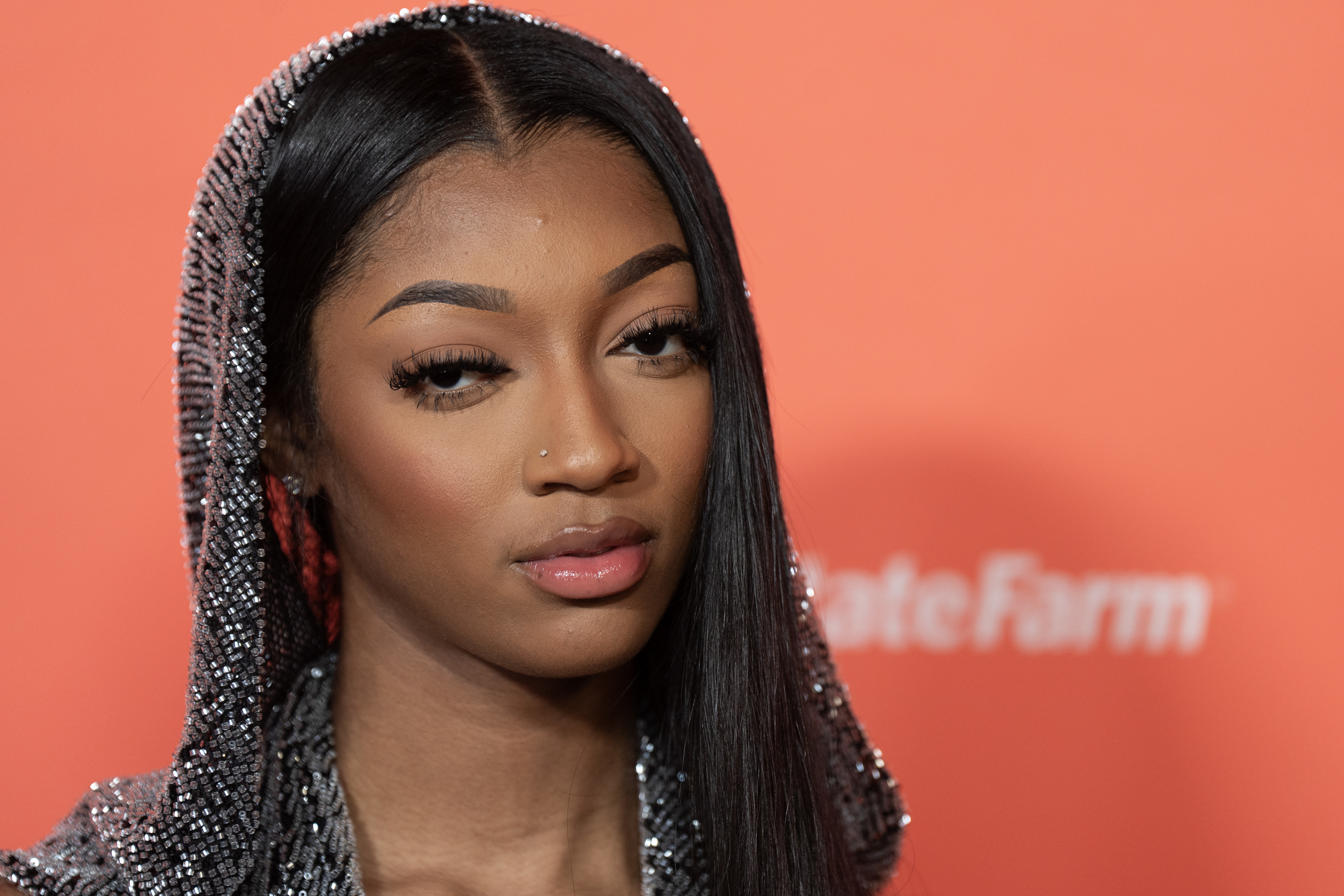 Woman in a hooded, sparkly outfit on a red carpet