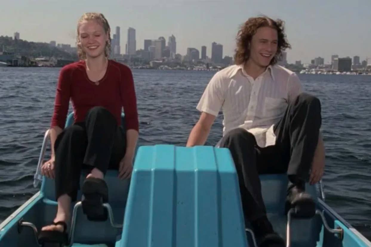 Two people, a man and a woman, sitting on a small boat with city skyline in the background