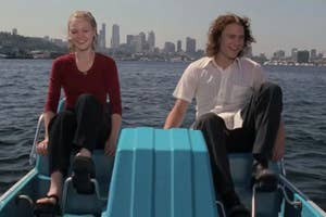 Two people, a man and a woman, sitting on a small boat with city skyline in the background