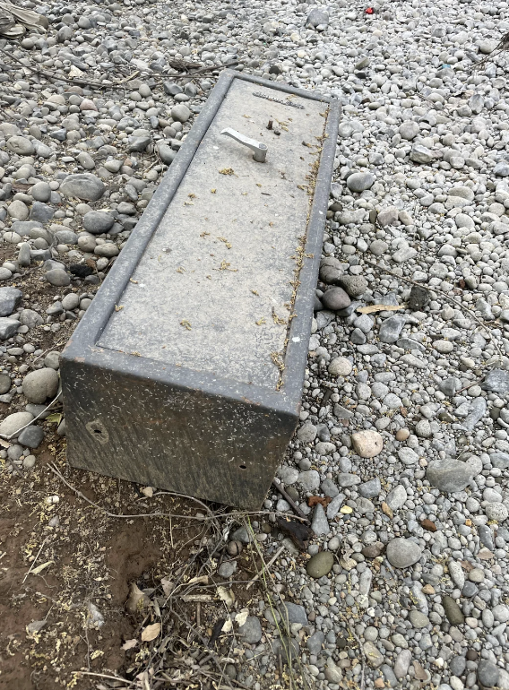 Rectangular bench on a pebble-covered ground, partially embedded in soil