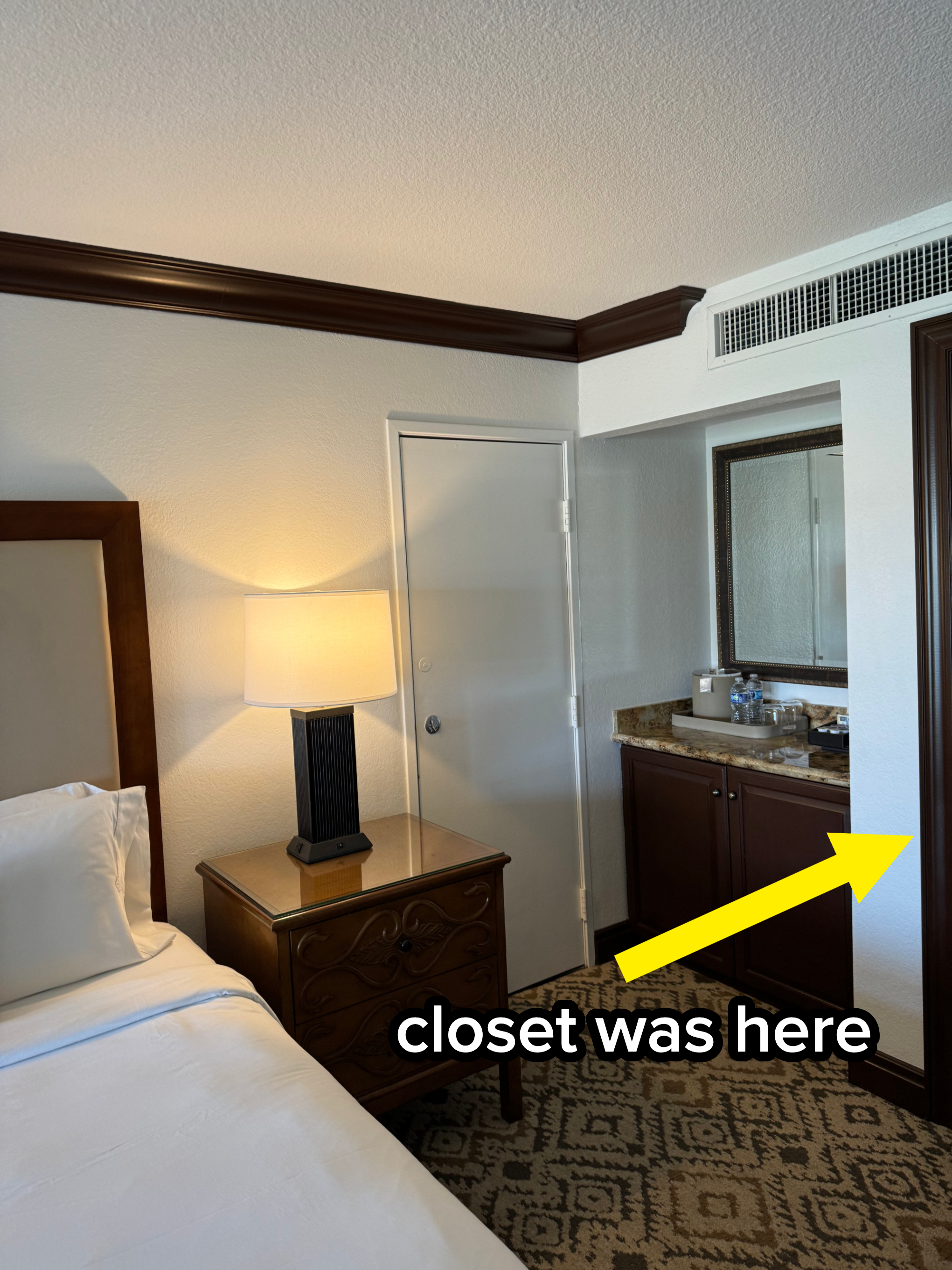 Hotel room with a bed, nightstand, lamp, and visible bathroom area