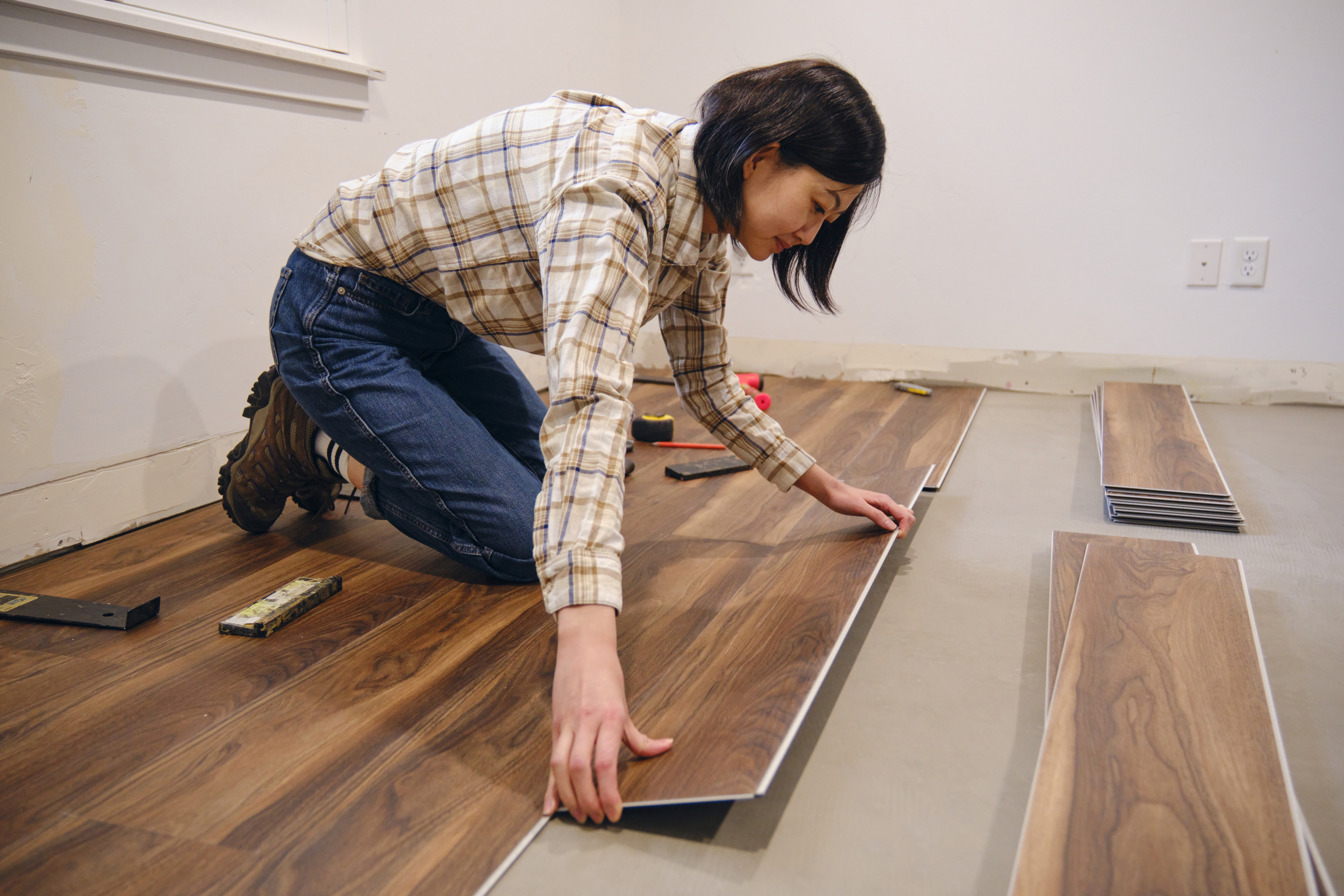 Person measuring wooden floor panels for installation