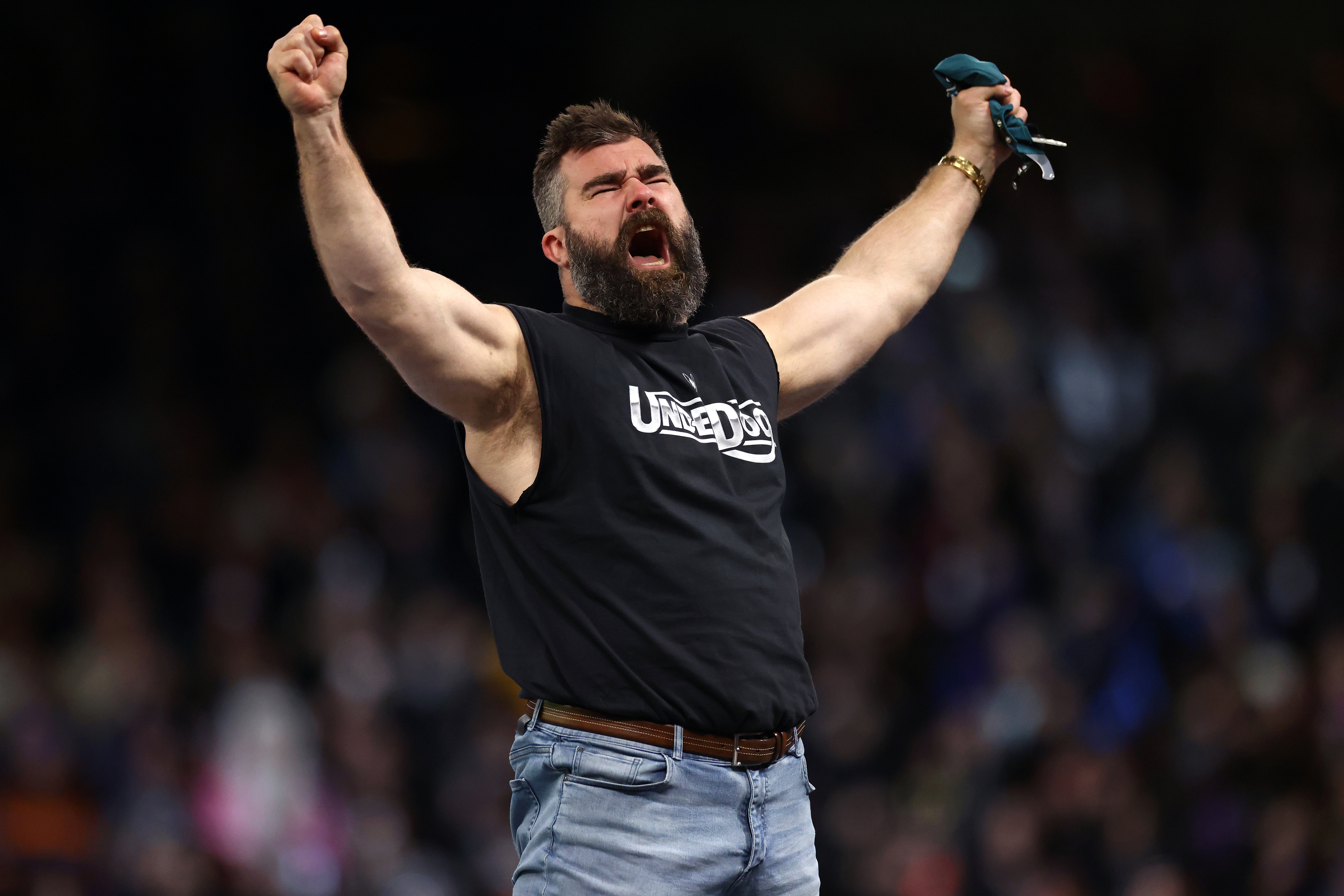 Man with beard in a t-shirt and jeans cheering with arms raised in victory