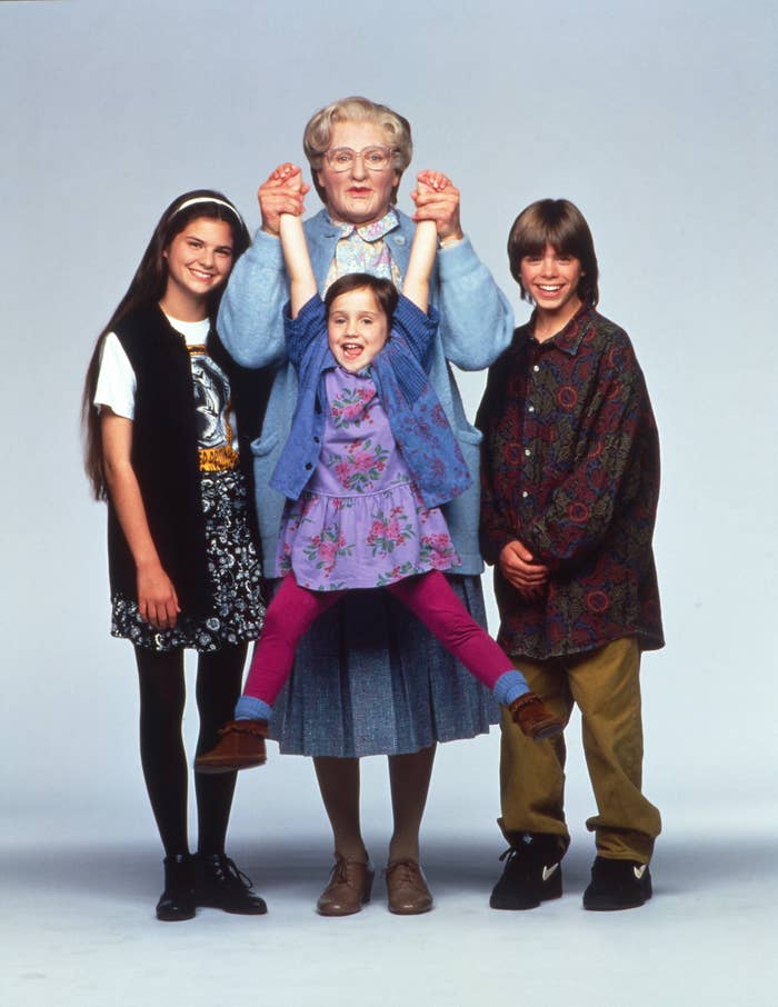 Promotional image of &#x27;Mrs. Doubtfire&#x27; characters posing together, with actor in elderly woman disguise center