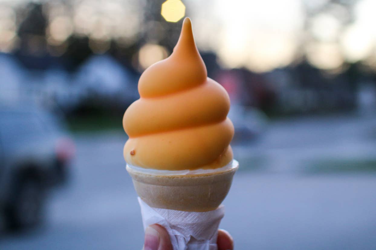 A person holding a swirled soft serve ice cream cone