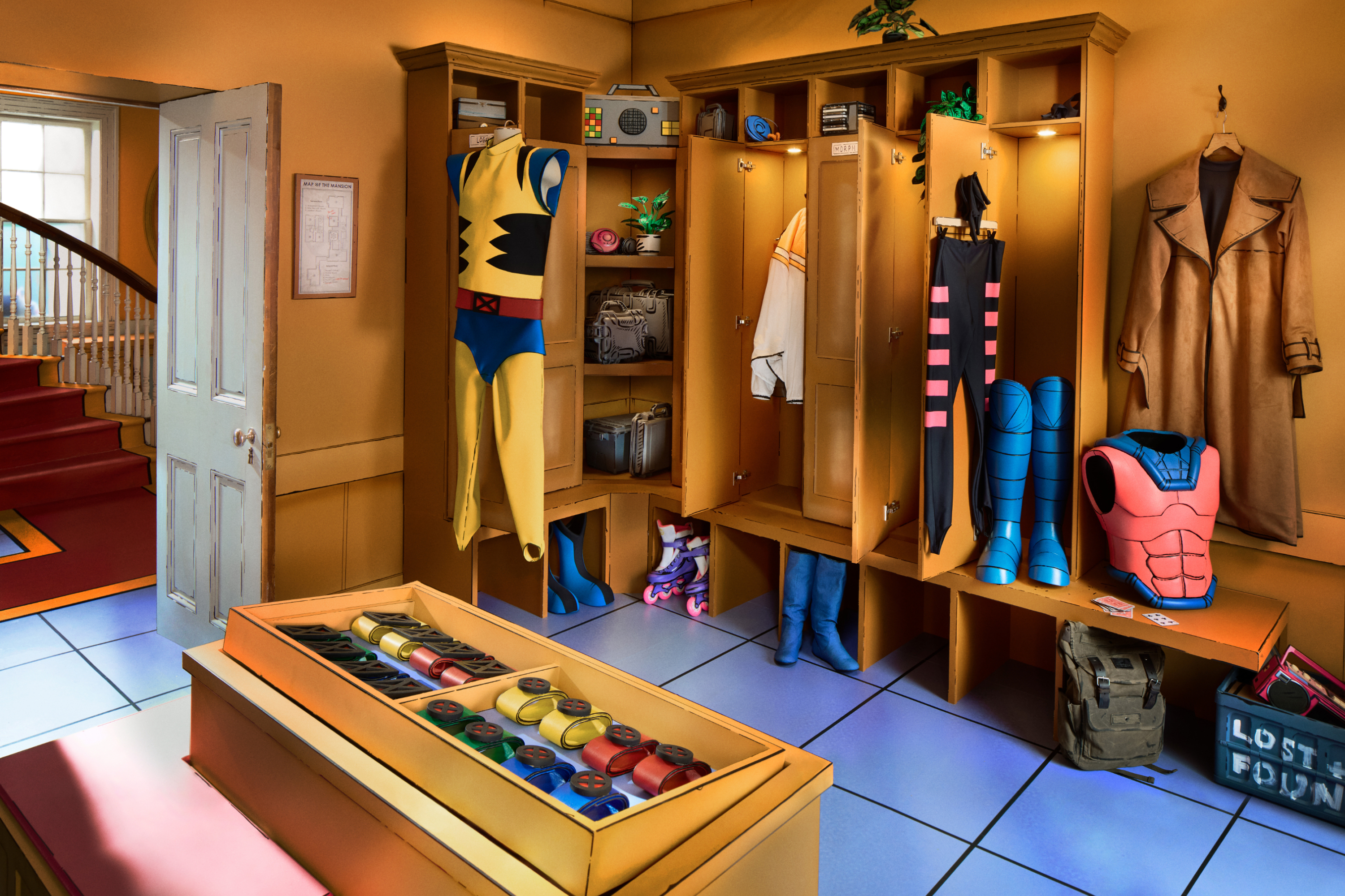 Lockers with superhero costumes and gadgets, a cape hanging on a door, and a trunk of masks on the floor
