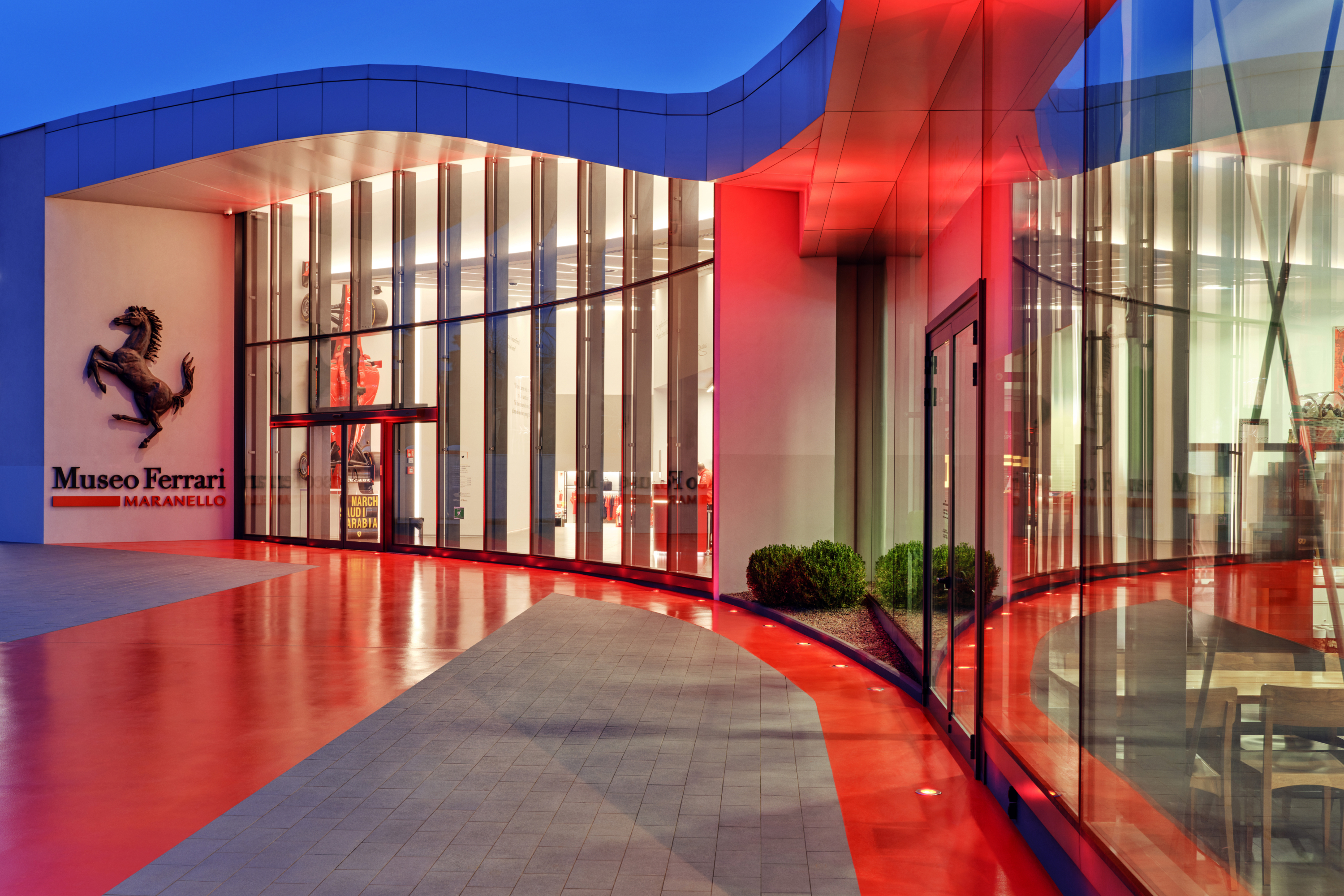 Exterior view of Museo Ferrari with lit facade and emblem, reflecting the brand&#x27;s automotive heritage