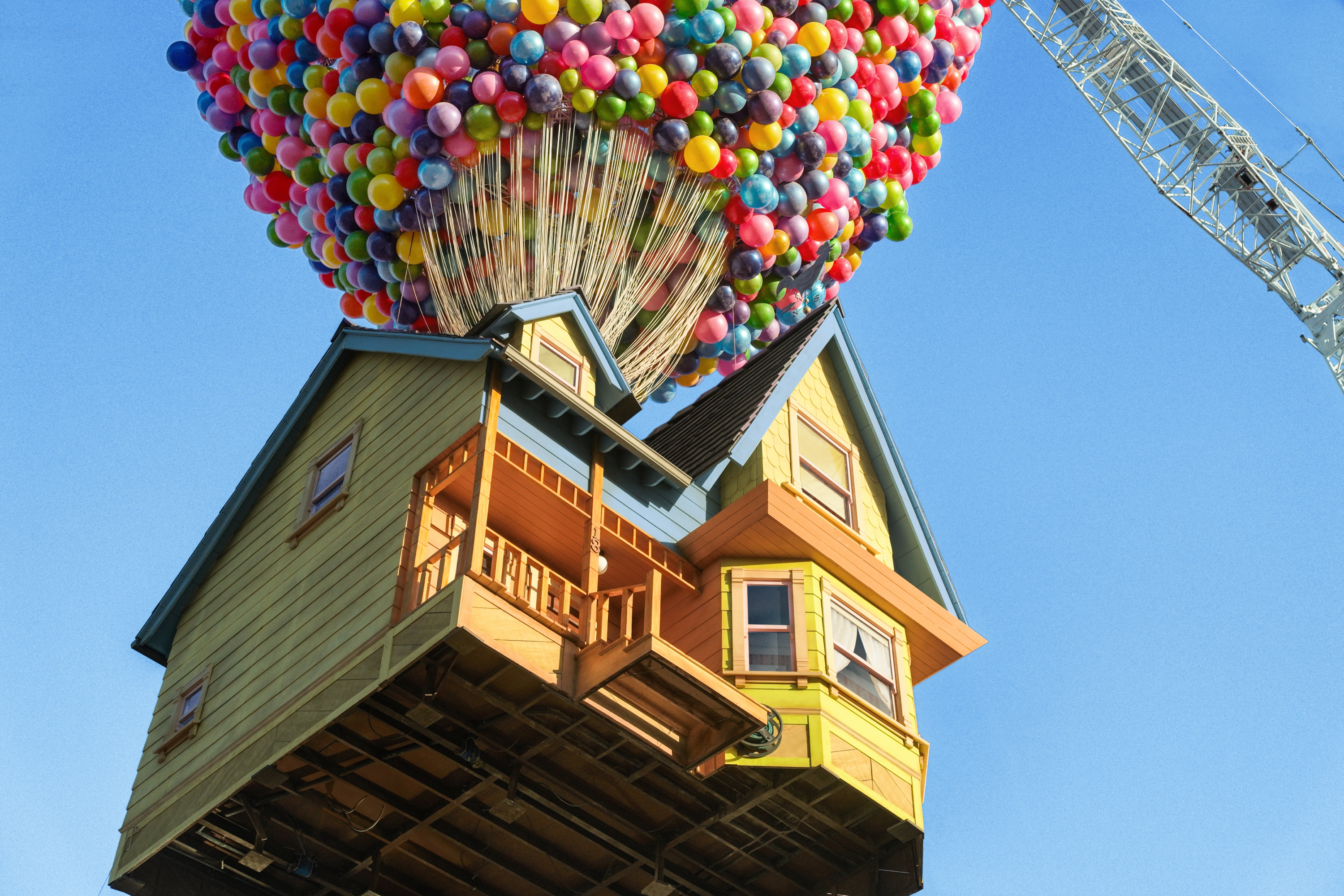 House lifted by myriad balloons against a blue sky, reminiscent of the animated film &quot;Up.&quot;