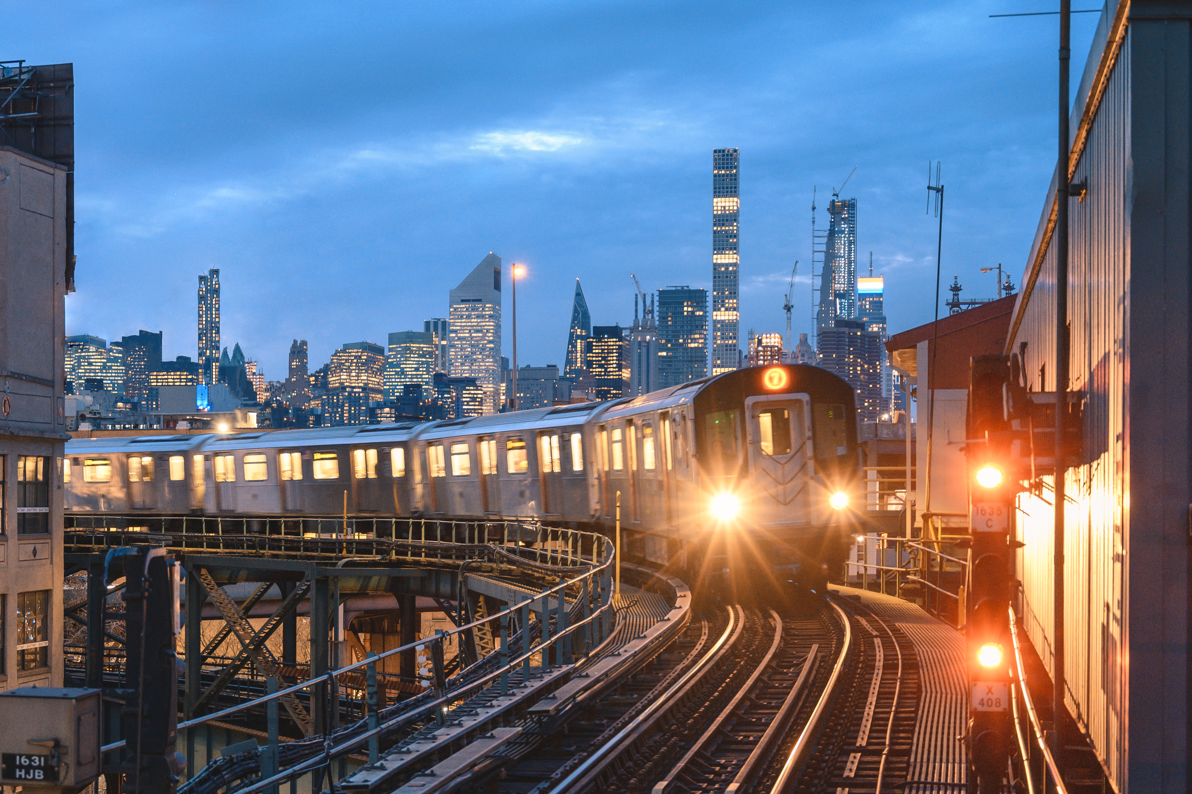 A train on elevated tracks with city skyline in the background at dusk