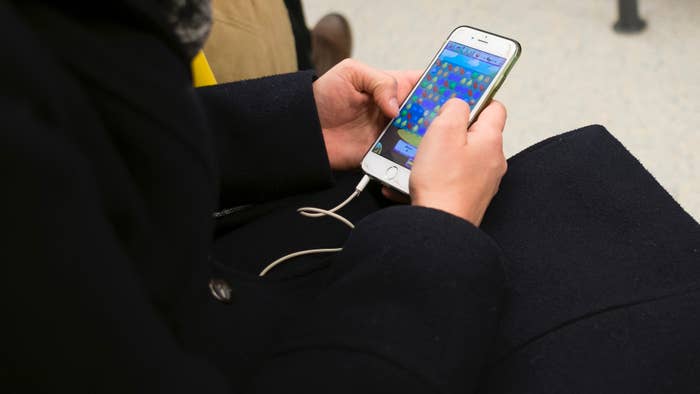 Person sitting and playing a game on a smartphone with earphones connected