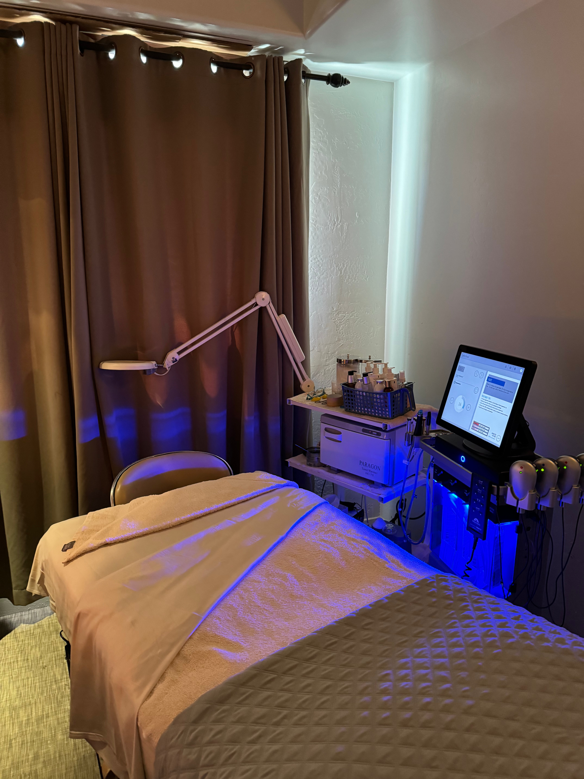 Massage table in a room with a computer setup and dim lighting, suggesting high-tech spa services for travelers
