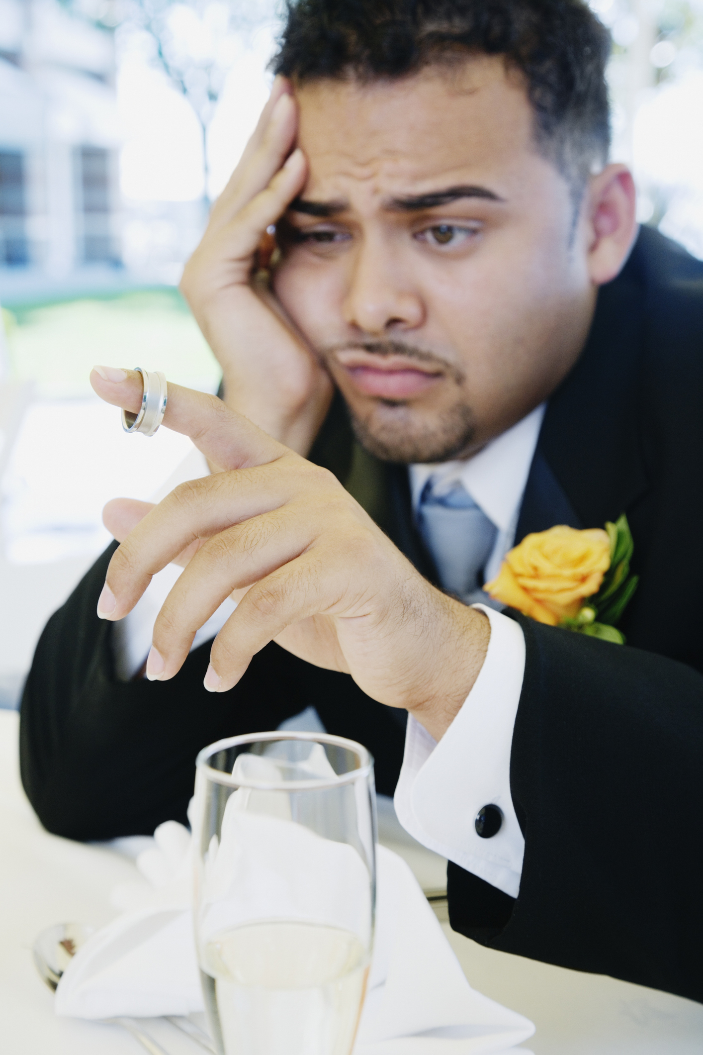 Man in a suit at a wedding appears concerned while looking at his wedding ring