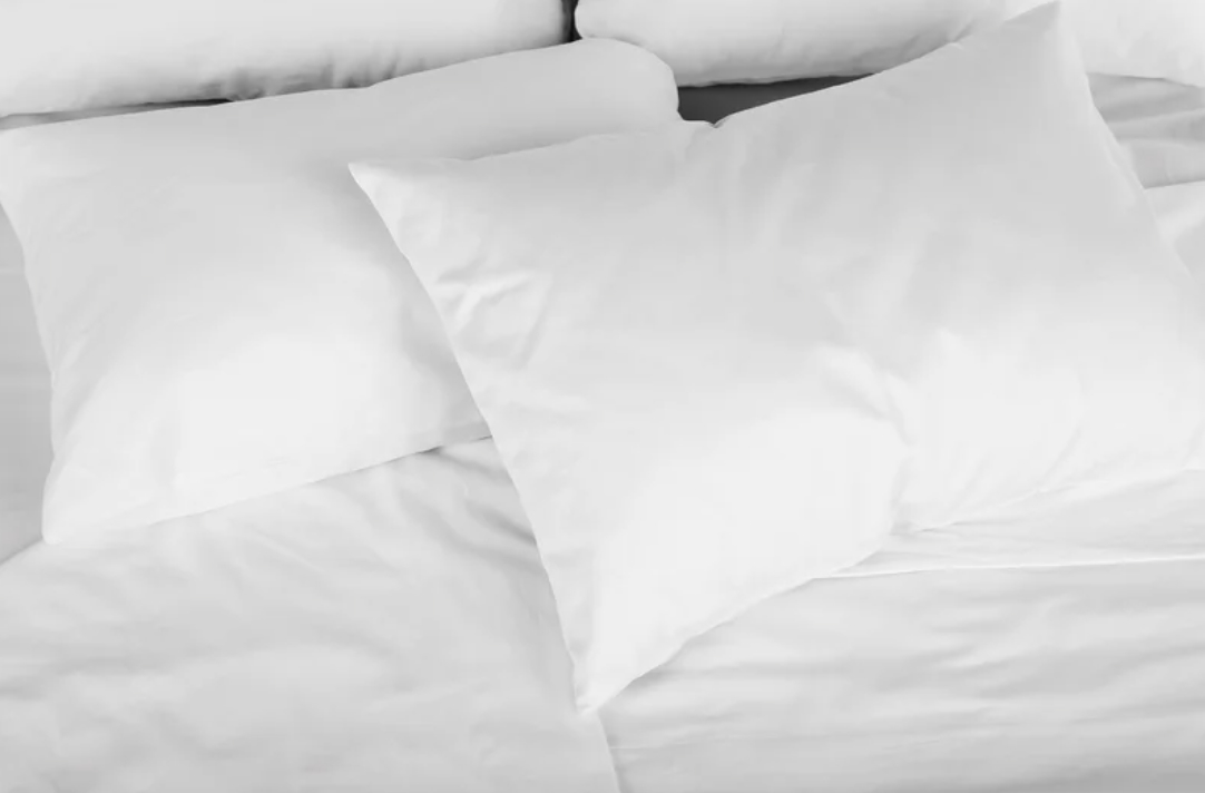 Four white pillows on an unmade bed