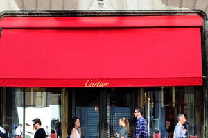Storefront awning with the 'Cartier' logo, people walking by on the sidewalk