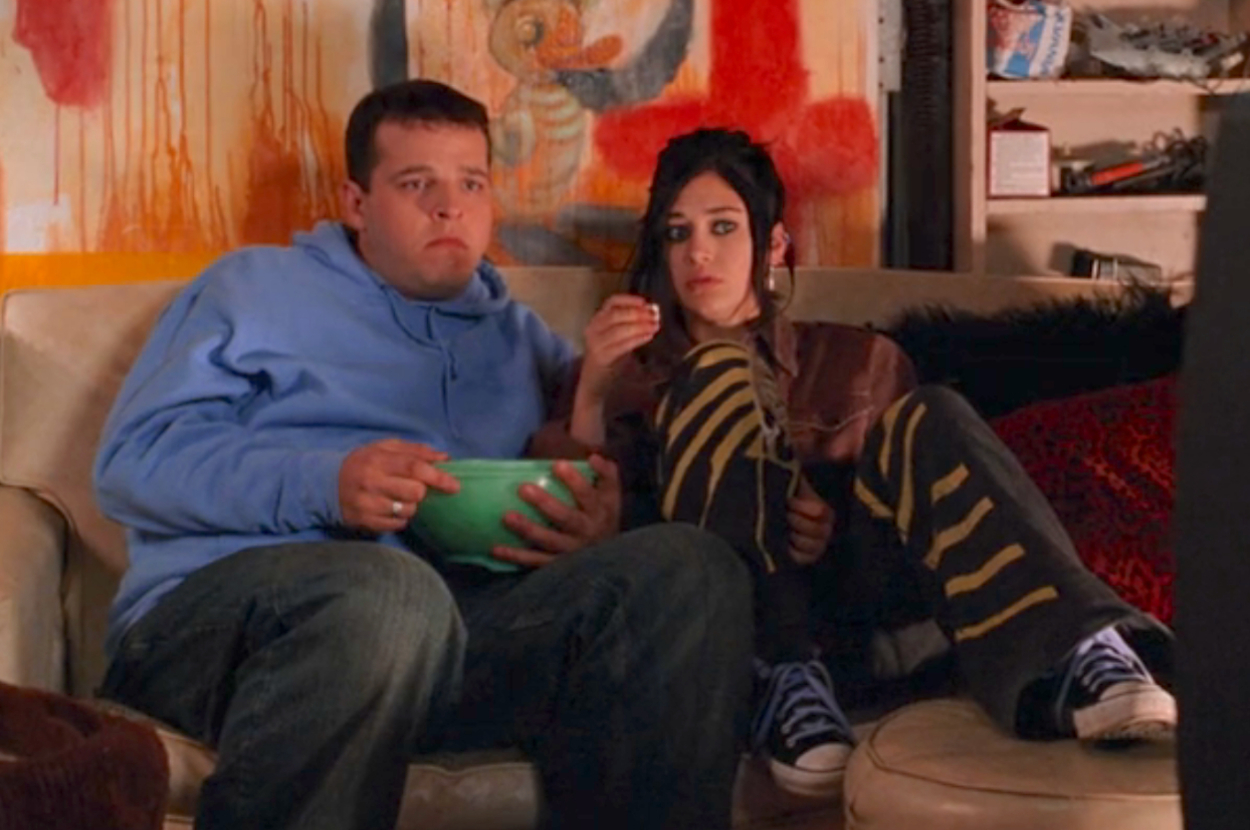 Damian and Janis from Mean Girls sitting on the couch eating popcorn and watching a movie