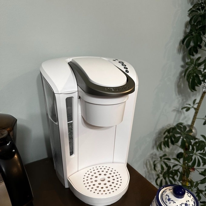 Single-serve coffee maker on a kitchen counter beside a plant
