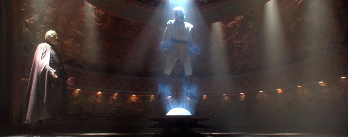 Two characters from Star Wars, a hologram of an alien figure and a person in a dark robe, stand inside a sci-fi themed room