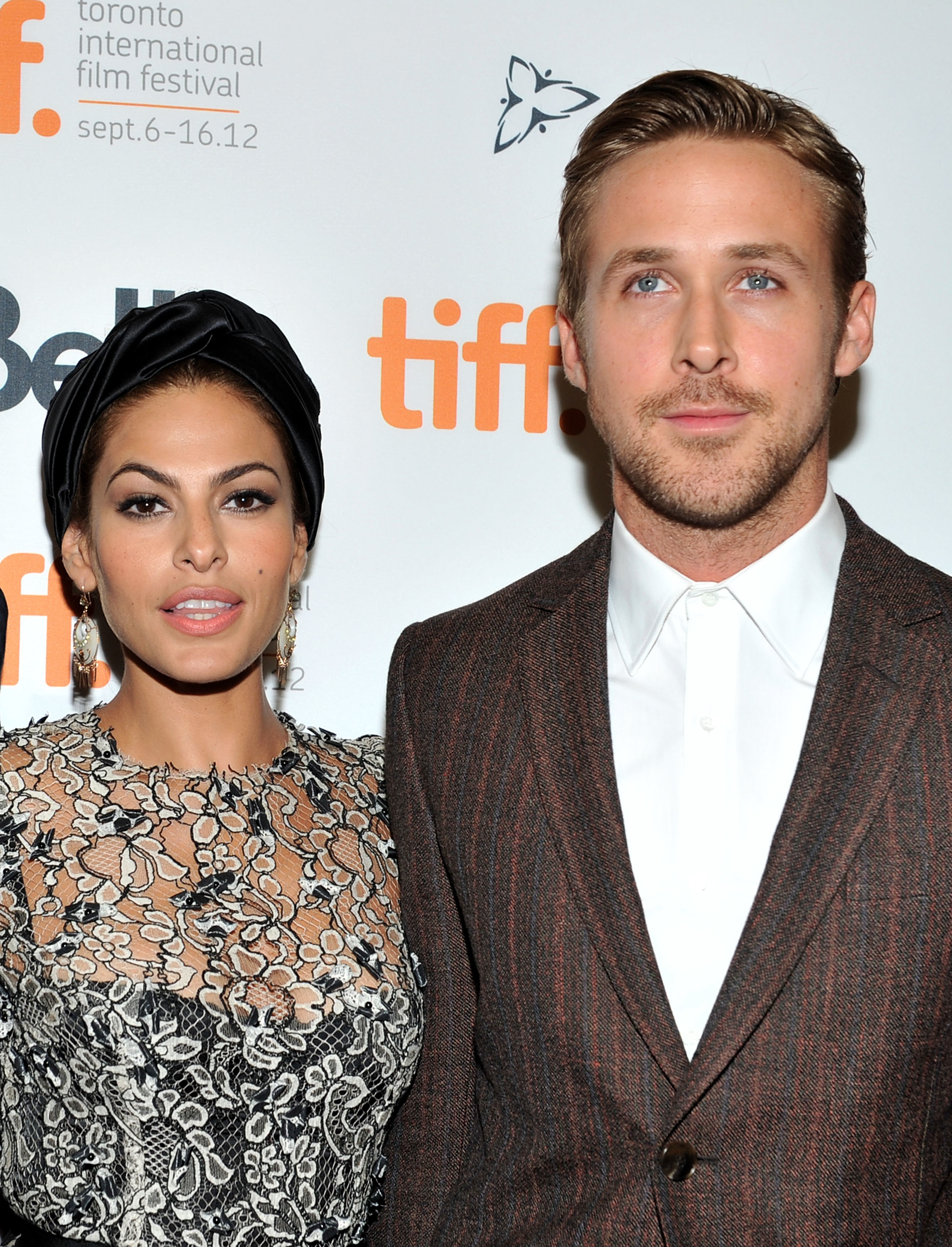 Eva Mendes in a lace dress stands with Ryan Gosling in a patterned suit at the TIFF event