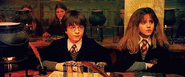 Harry Potter y Hermione Granger en clase de pociones, sorprendidos, con caldero y frascos en la mesa