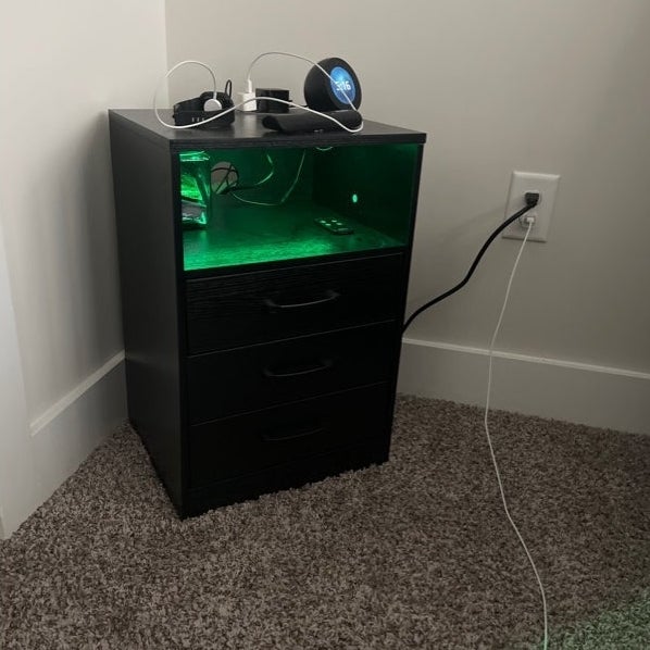 Black cabinet with LED lighting, housing tech equipment, by a power outlet
