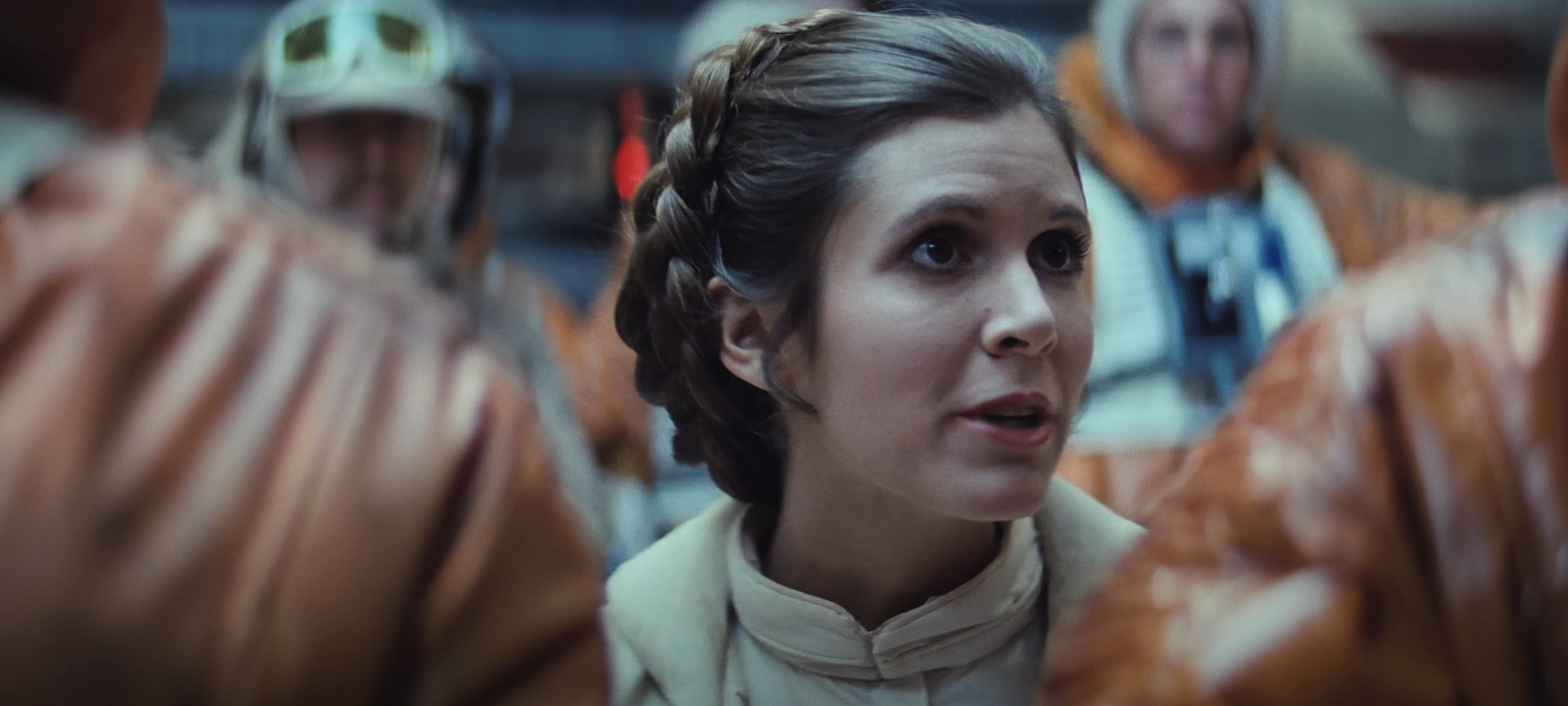 Princess Leia in white robe with hair buns, surrounded by Rebel fighters in orange jumpsuits