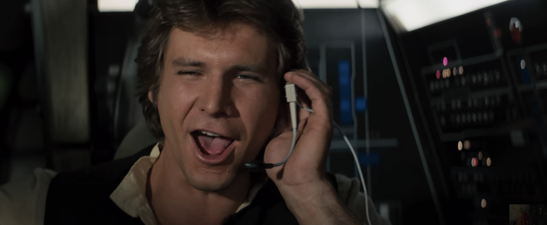 Harrison Ford as Han Solo smiles with a headset in the Millennium Falcon cockpit