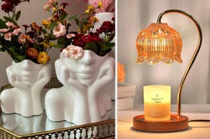 reviewer's two white vases shaped like heads holding flowers/ warmer lamp being used on candle