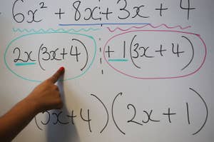 Person pointing to a whiteboard with mathematical expressions circled for teaching or explanation