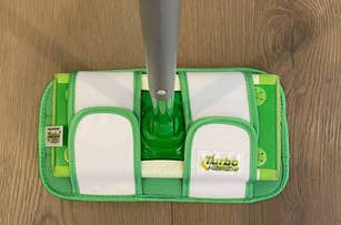 A swiffer mop with a reusable mop pad attached