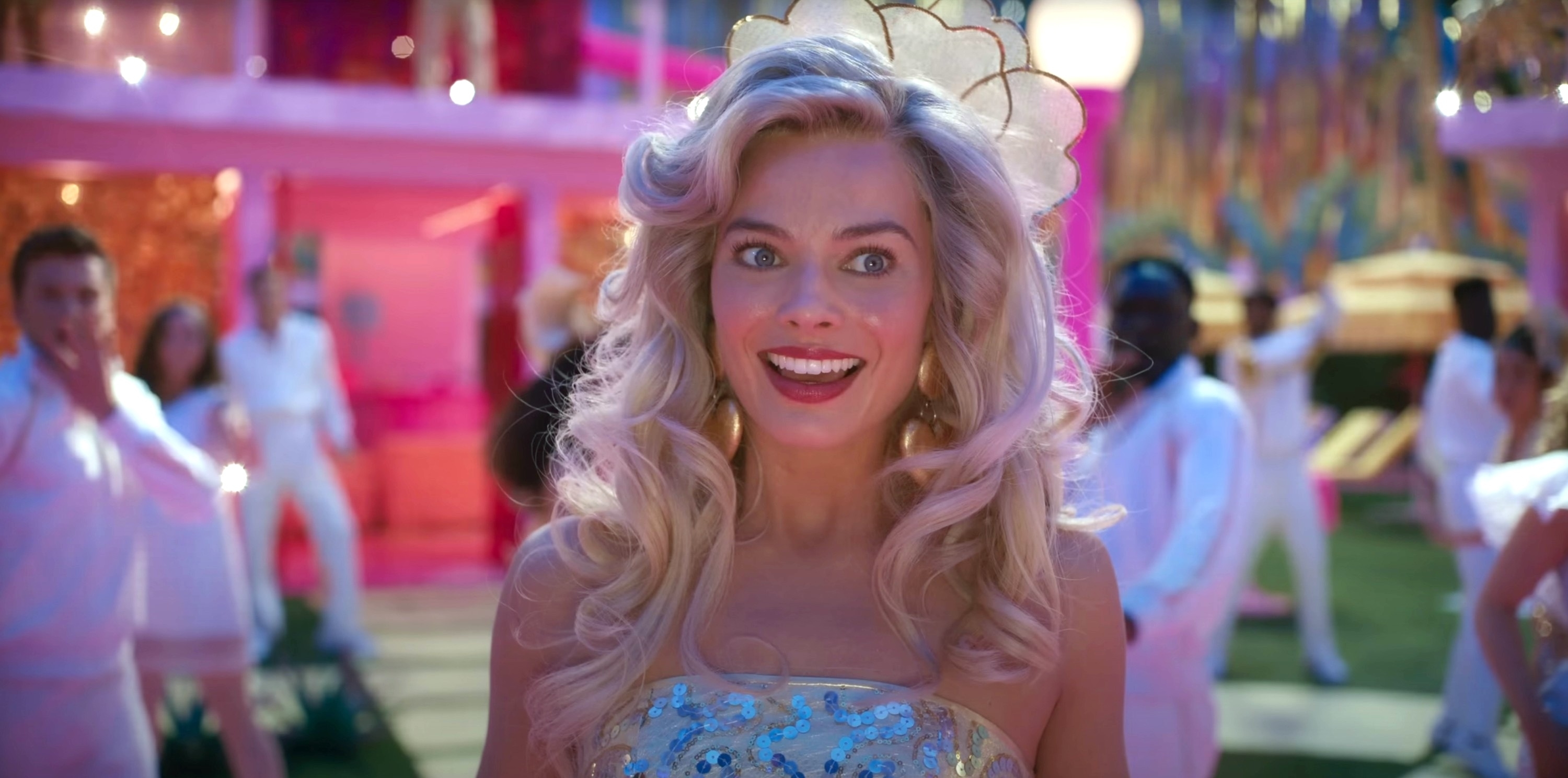 Animated character Barbie from a film wearing a sparkling dress and tiara, with a joyful expression in a party scene