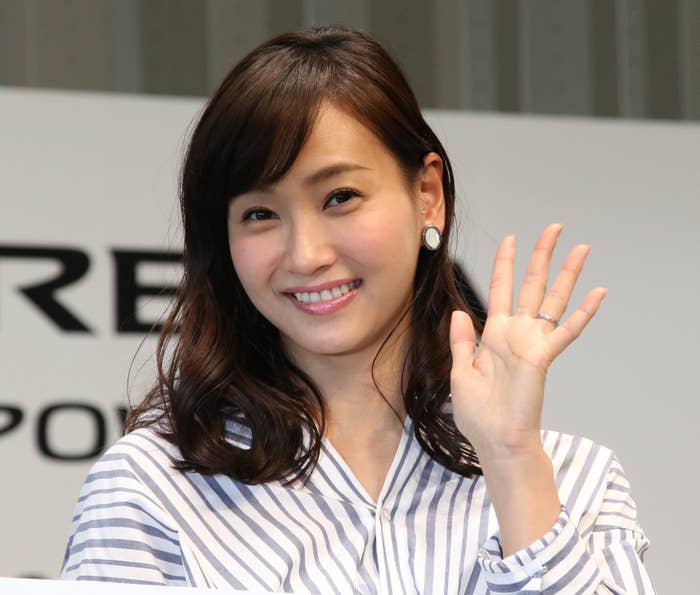 ストライプの服を着た女性が笑顔で手を振っています。