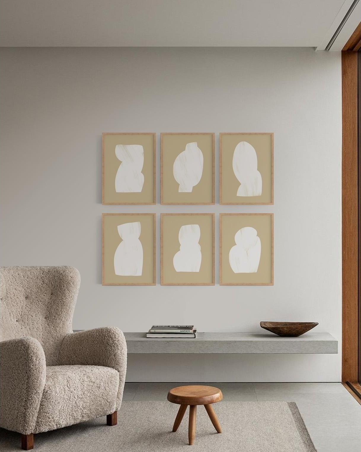 Six framed silhouettes on a wall above a sofa, with a side table and a wooden stool in a minimalist room