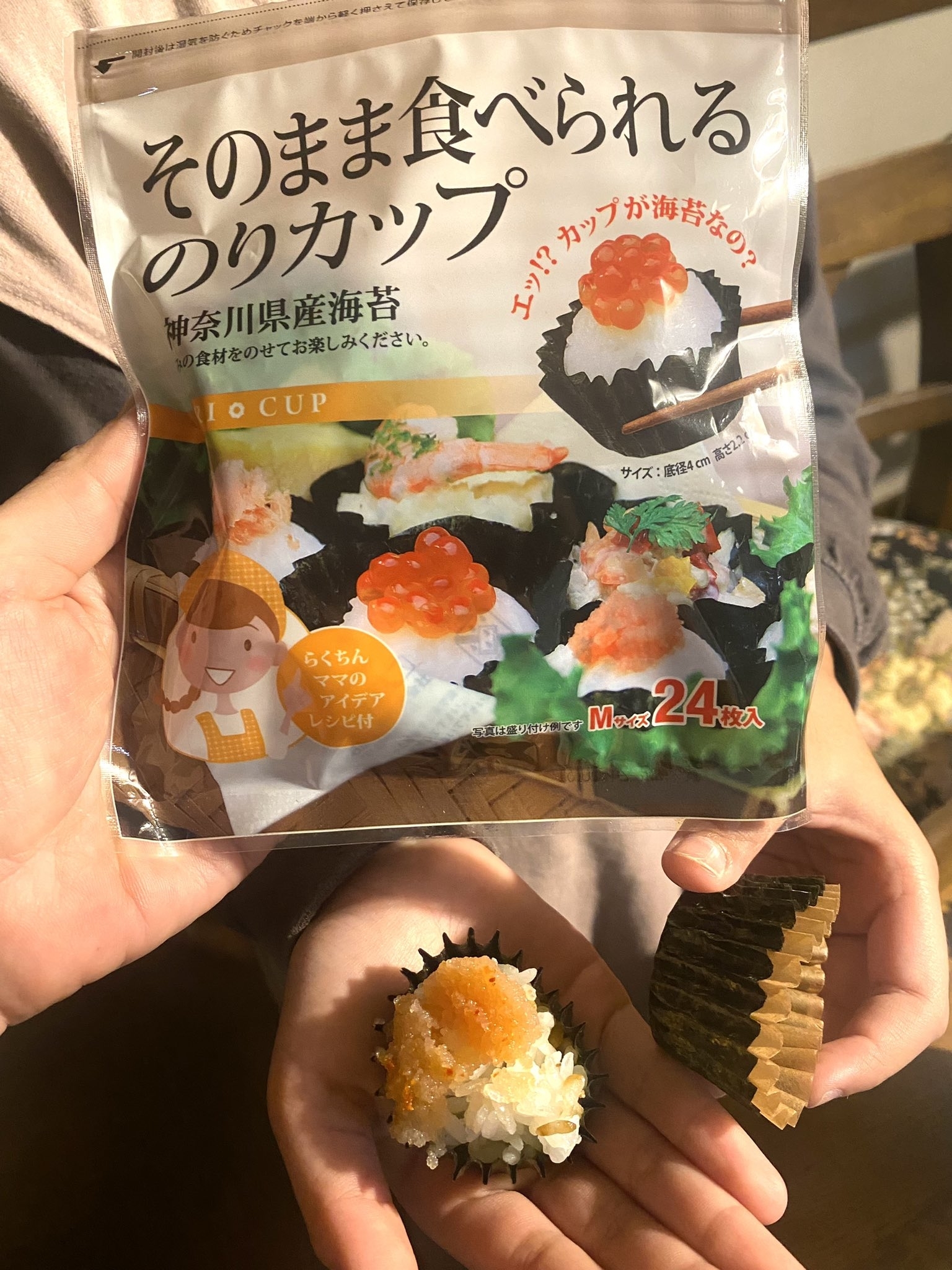 手に持たれた手巻き寿司形のお菓子のパッケージ。手巻き寿司の見た目を模した24個のスナック。