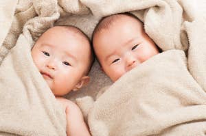 二人の赤ちゃんが毛布にくるまって横になっている。