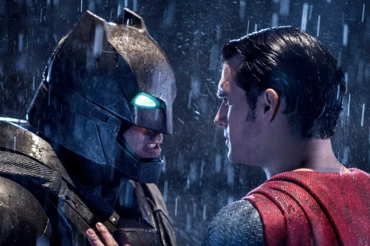 Batman and Superman facing each other under the rain, expressions tense