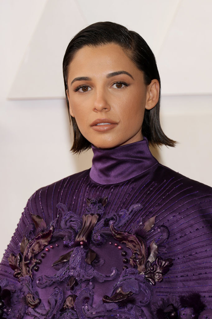 Naomi Scott in an elegant, high-neck dress with ornate detailing on the red carpet
