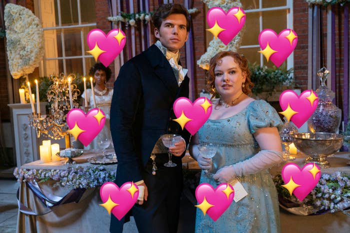 Nicola Coughlan and Luke Newton are holding drinks at a lavishly decorated indoor event, with candles and flowers in the background