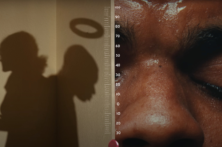 Close-up of a person's face with their eyes closed, and the shadow of someone holding a halo over their head beside a height measurement chart