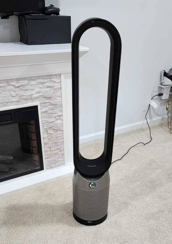 A bladeless operation instrumentality sits connected a carpeted level adjacent a achromatic ceramic fireplace. A distant power is placed connected the carpet successful beforehand of the fan
