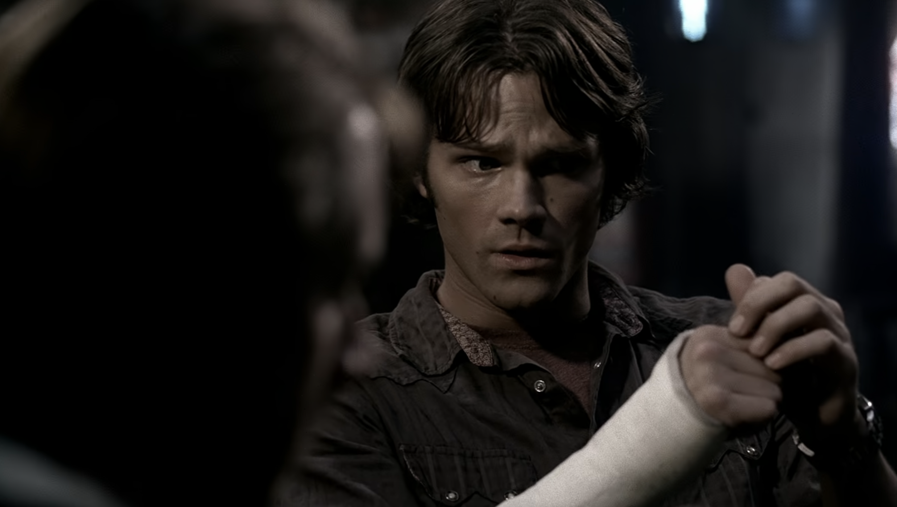 Jared Padalecki as Sam Winchester, in a scene from "Supernatural," looking intently with a cast on his right arm
