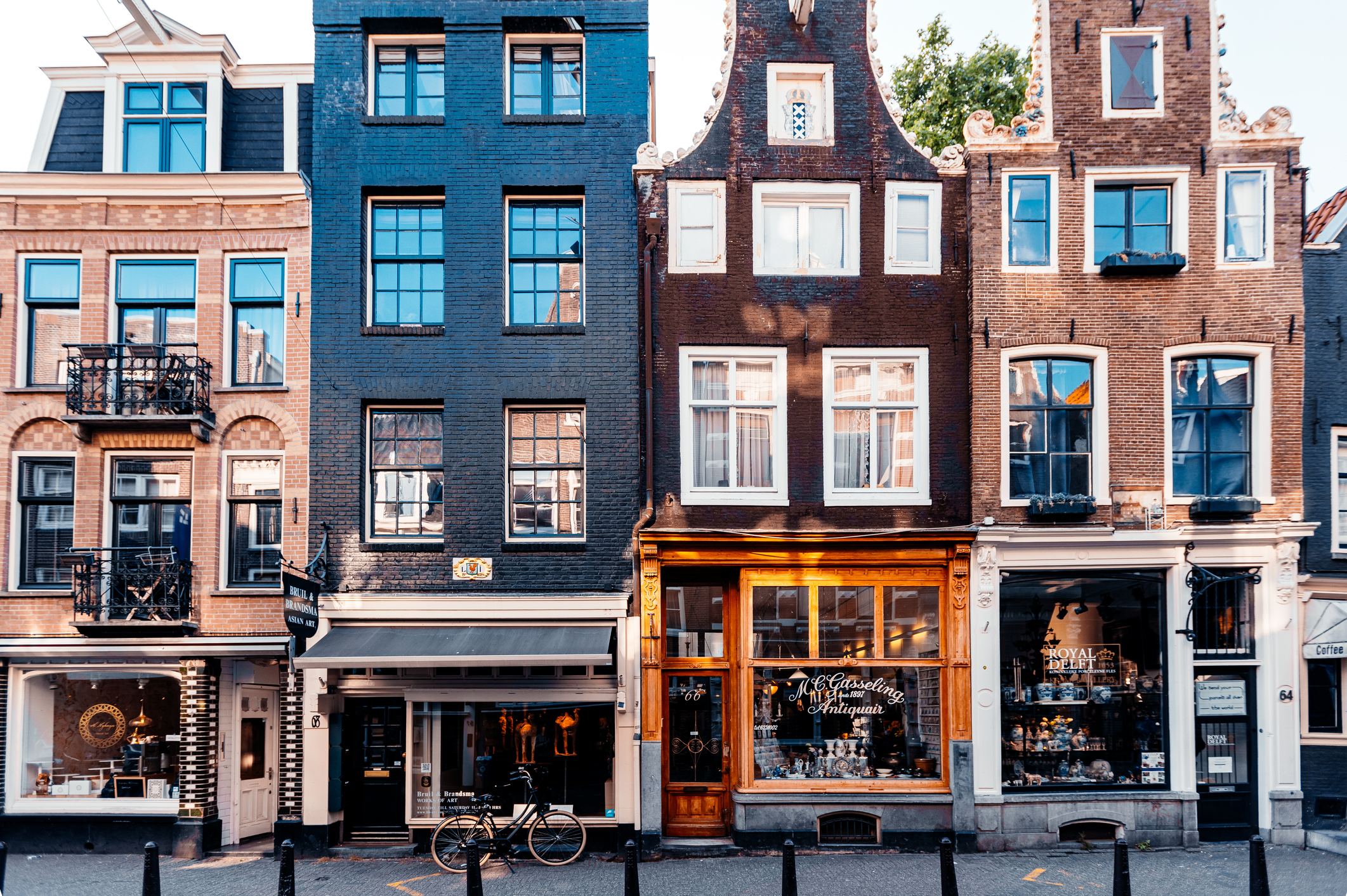 Row of traditional European storefront buildings with varied architectural designs and a few bicycles parked outside