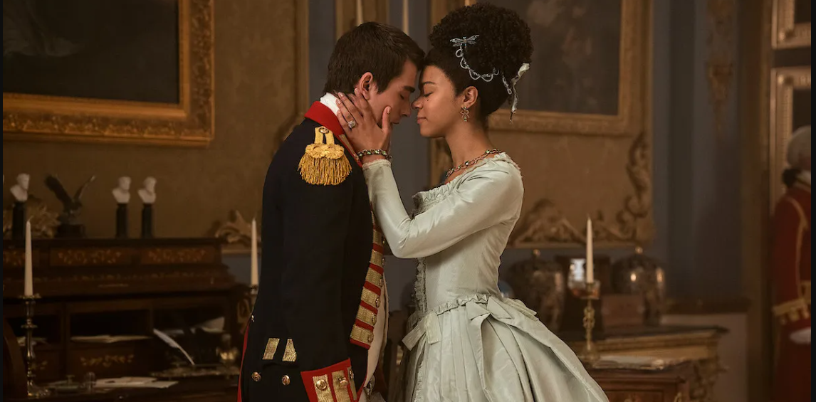 Escena del libro "Queen Charlotte: A Bridgerton Story" con dos personajes vestidos con trajes de época en un abrazo romántico