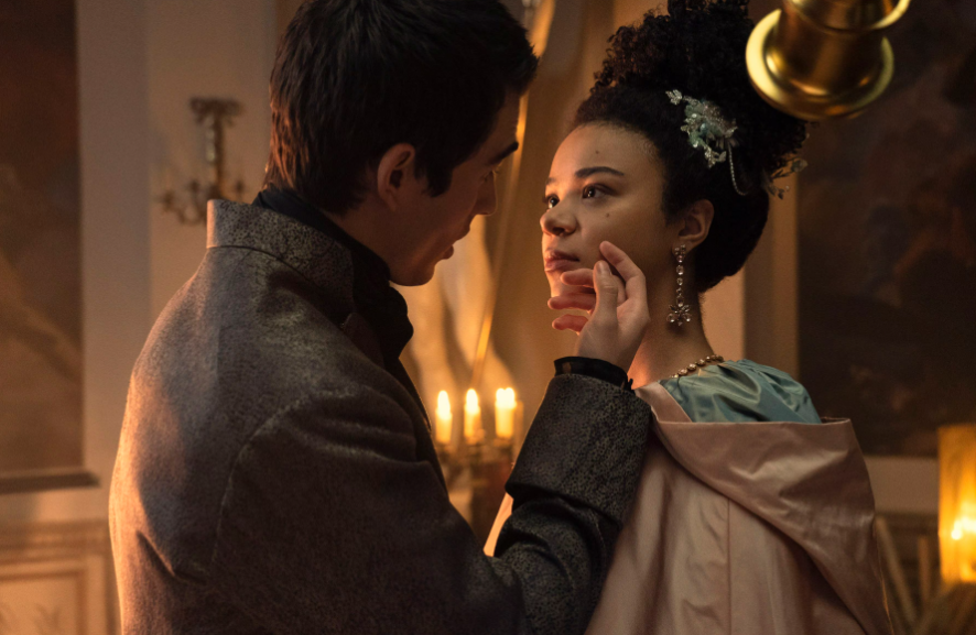 Fotograma de "La reina Carlota: Una historia de Bridgerton" con Corey Mylchreest sosteniendo el rostro de India Amarteifio en una escena romántica
