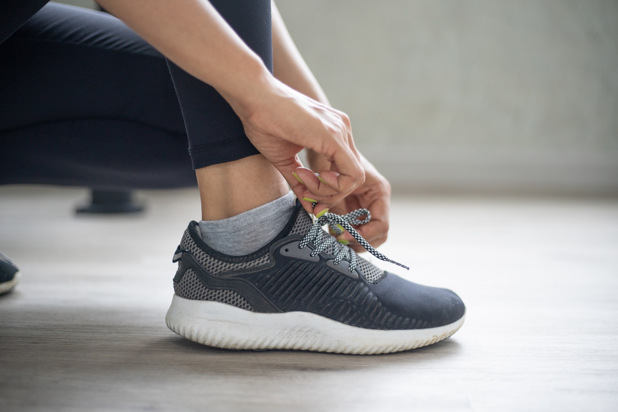 A person is tying their shoelaces on a sporty, comfortable sneaker. The image focuses on their hands and feet, highlighting the attention to detail in securing the laces