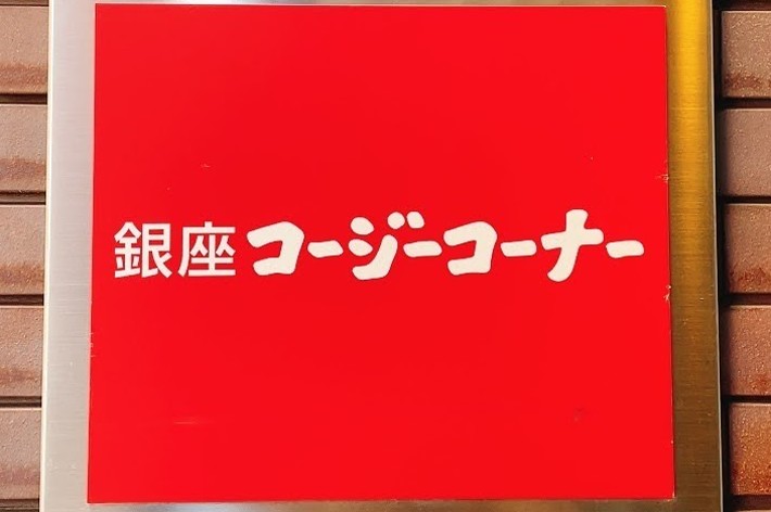 Sign with Japanese characters on red background, mounted on a brick wall