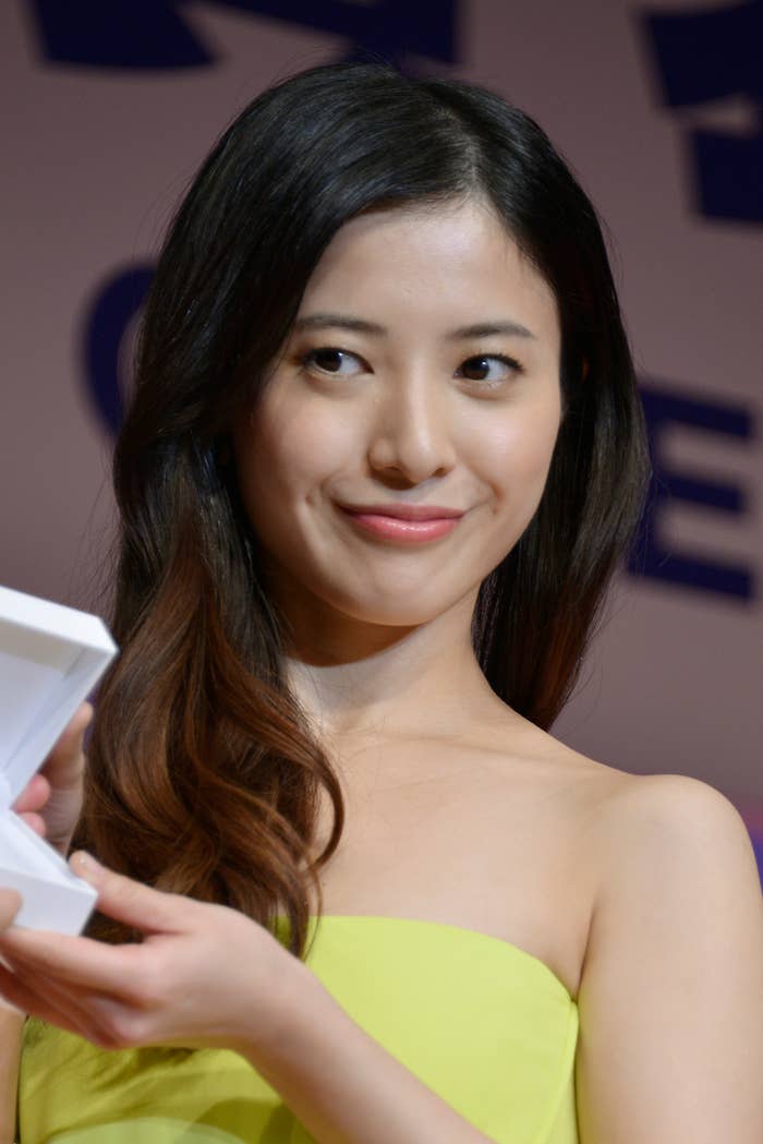 女性が笑顔でカメラに向かって小さな箱を持っている。