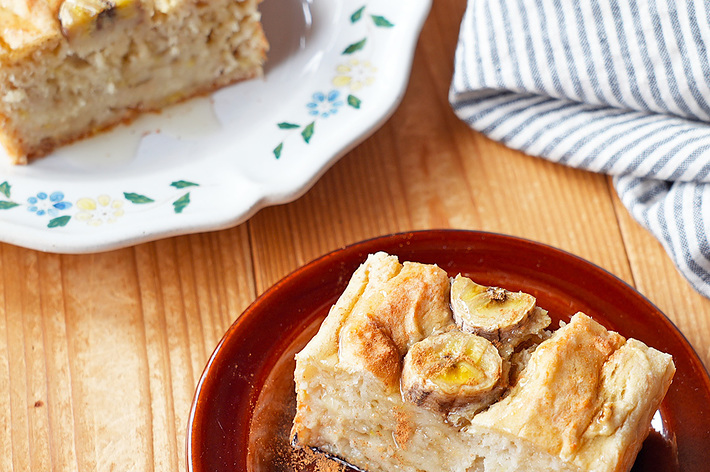 バナナのスライスがトッピングされた焼き立てのバナナブレッドが茶色の皿に盛られている。