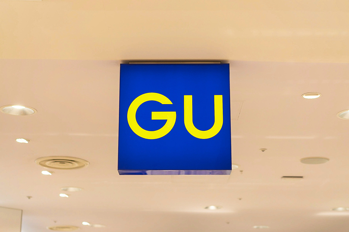 Sign with letters &ldquo;GU&rdquo; hanging from a ceiling in a well-lit indoor space