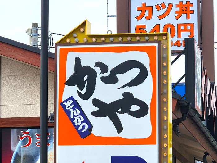 とんかつの看板が見える。『かつや』『540円』と書かれている。
