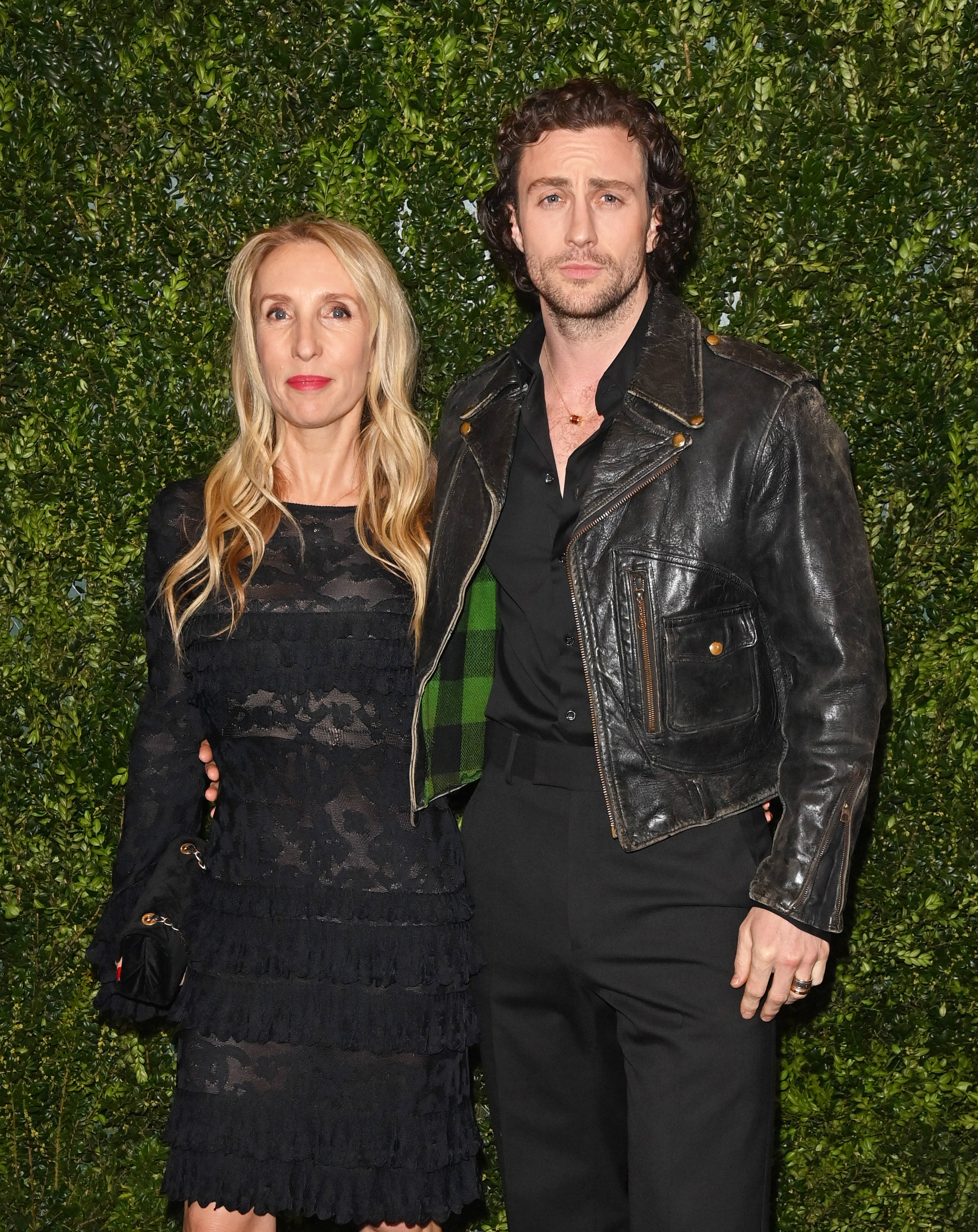 Sam Taylor-Johnson in a lacy dress and Aaron Taylor-Johnson in a leather jacket, posing together at a formal event